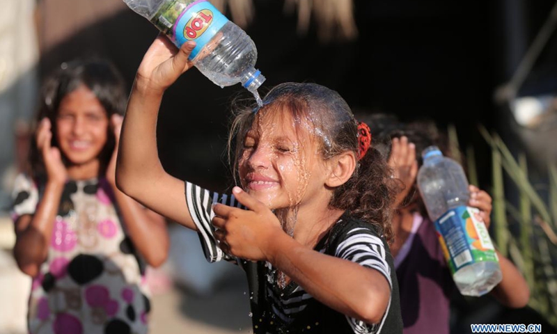 A Palestinian girl pours water to cool off during hot weather near Khan Younis refugee camp in southern Gaza Strip, on June 29, 2021.(Photo: Xinhua)
