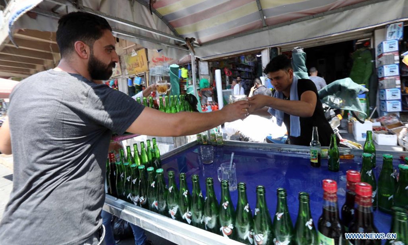 A seller hands a glass of cold drink to a customer in Baghdad, Iraq, on June 29, 2021. Scorching weather started here in June and temperatures rose to about 50 degrees Celsius.(Photo: Xinhua)