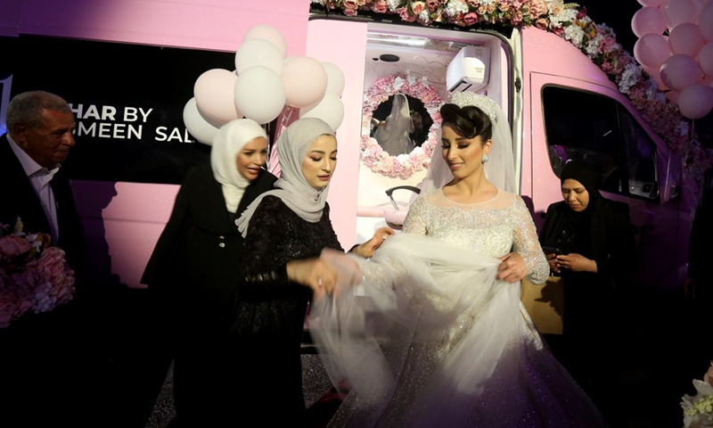 A Palestinian bride is seen outside a mobile beauty salon in the West Bank city of Nablus, on June 28, 2021.(Photo: Xinhua)