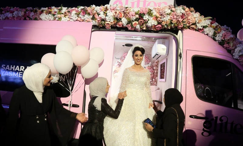 A Palestinian bride is seen outside a mobile beauty salon after getting her wedding makeup done, in the West Bank city of Nablus, on June 28, 2021.(Photo: Xinhua)