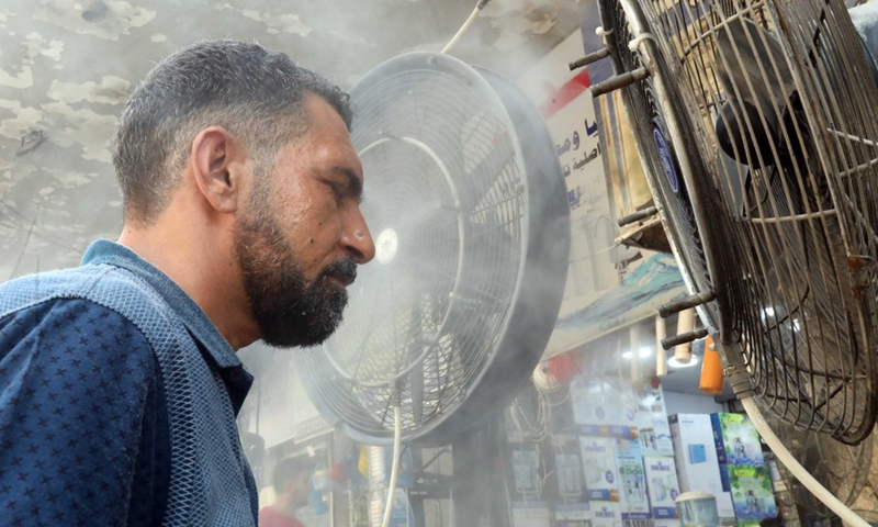 A man stands in front of a fan to cool off at a market in central Baghdad, Iraq, on June 29, 2021.(Photo: Xinhua)