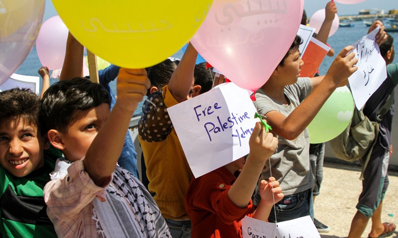 Palestinian children hold balloons attached with messages before releasing them into the sky, at the fishing port in Gaza City, on June 30, 2021.(Photo: Xinhua)