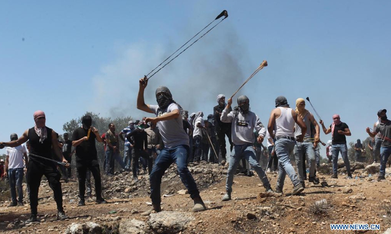 Protesters use slingshots to hurl stones at Israeli soldiers and members of Israeli border police during clashes following a protest against the expanding of Jewish settlements in the village of Beita, south of the West Bank city of Nablus, July 2, 2021.Photo:Xinhua
