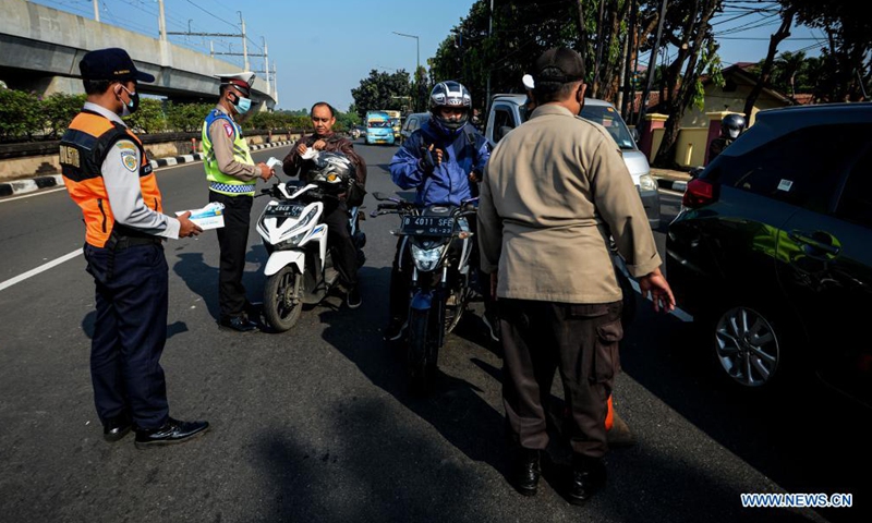 A police officer gives a face mask to a man in Jakarta, Indonesia, July 3, 2021. The Indonesian government has decided to deploy 53,000 personnel for emergency community activity restrictions (locally known as PPKM) to be imposed in Java and Bali from July 3 to 20, a senior police officer said on Friday.Photo:Xinhua