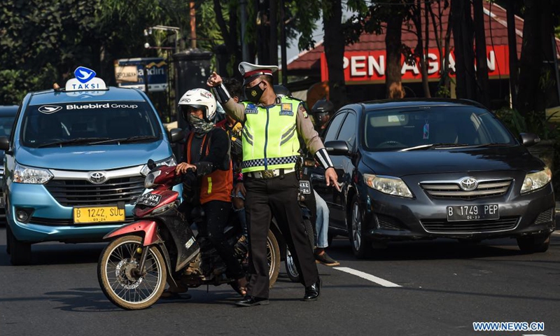 A police officer asks a man without a proper face cover to pull over to the side of the road in Jakarta, Indonesia, July 3, 2021. The Indonesian government has decided to deploy 53,000 personnel for emergency community activity restrictions (locally known as PPKM) to be imposed in Java and Bali from July 3 to 20, a senior police officer said on Friday.Photo:Xinhua