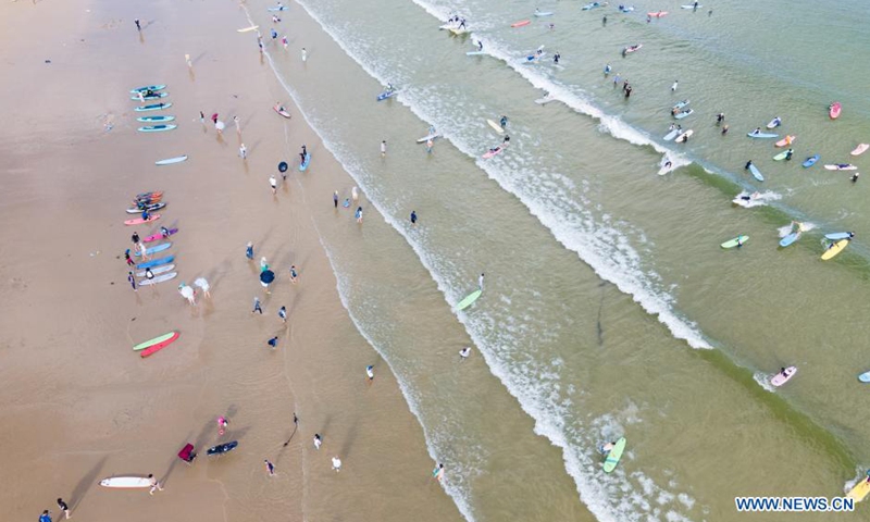 Tourists surf in the water of Tenghai fishing village in Sanya, south China's Hainan Province, July 9, 2021. Located in Haitang bay of Sanya, Tenghai fishing village has attracted lots of tourists by developing tourism, surfing and homestay industries since 2018.Photo:Xinhua