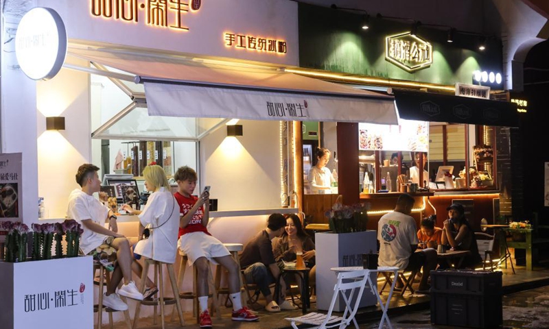 Tourists enjoy their time at a bar in Tenghai fishing village in Sanya, south China's Hainan Province, July 8, 2021. Located in Haitang bay of Sanya, Tenghai fishing village has attracted lots of tourists by developing tourism, surfing and homestay industries since 2018. Photo:Xinhua