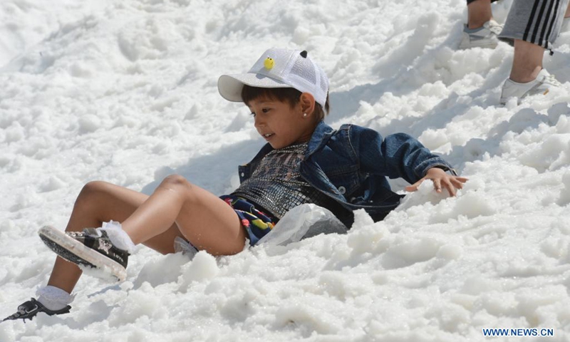 A child plays with snow along the Duku Highway in northwest China's Xinjiang Uygur Autonomous Region, July 9, 2021. The 560-km highway, connecting Dushanzi in the northern area of Xinjiang Uygur Autonomous Region and Kuqa City in the south, runs through various landscapes including glaciers, forests, and grasslands.(Photo: Xinhua)