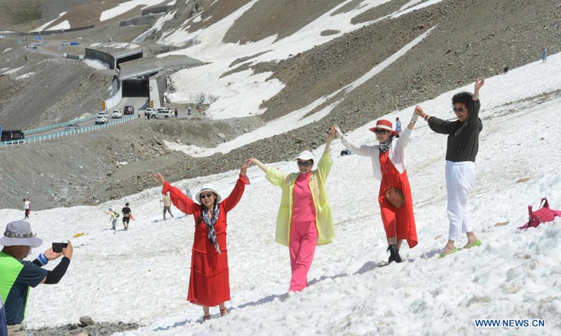 Tourists pose for a photo along the Duku Highway in northwest China's Xinjiang Uygur Autonomous Region, July 9, 2021. The 560-km highway, connecting Dushanzi in the northern area of Xinjiang Uygur Autonomous Region and Kuqa City in the south, runs through various landscapes including glaciers, forests, and grasslands.(Photo: Xinhua)