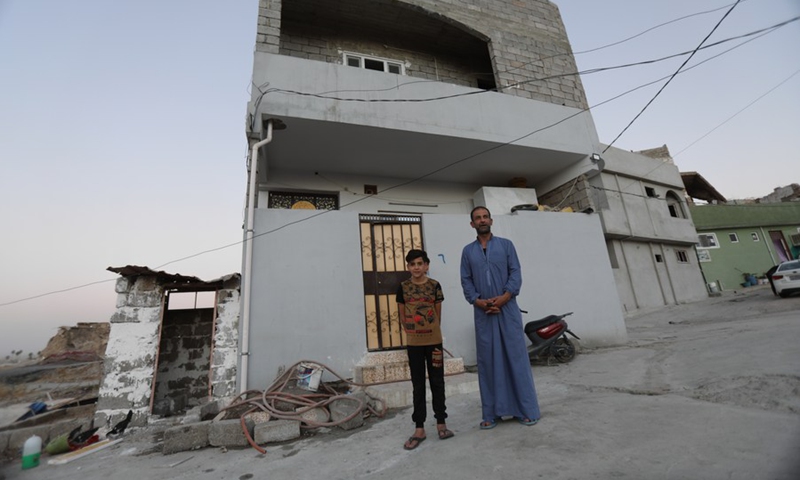 Photo taken on July 3, 2021 shows Ali Saadi and his son stand in front of his newly-built house in Mosul, Iraq.(Photo: Xinhua)