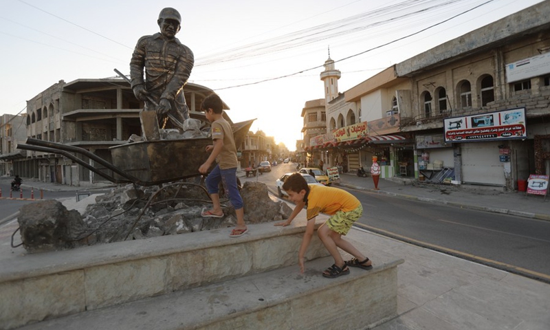 Photo taken on July 3, 2021 shows children paly at a statue in Mosul, Iraq.(Photo: Xinhua)