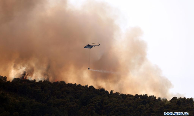 A firefighting helicopter pours water on a forest fire on the Island of Ciovo in Croatia, on July 10, 2021(Photo: Xinhua)