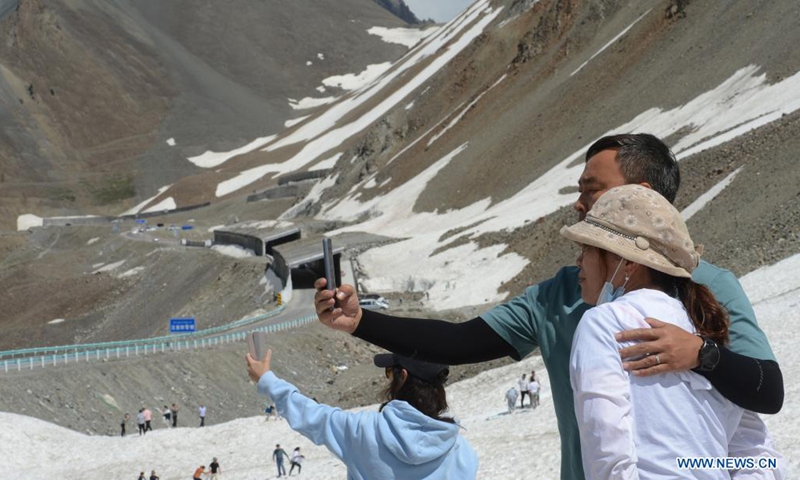 Tourists take selfies with snow mountains along the Duku Highway in northwest China's Xinjiang Uygur Autonomous Region, July 9, 2021. The 560-km highway, connecting Dushanzi in the northern area of Xinjiang Uygur Autonomous Region and Kuqa City in the south, runs through various landscapes including glaciers, forests, and grasslands. (Photo: Xinhua)