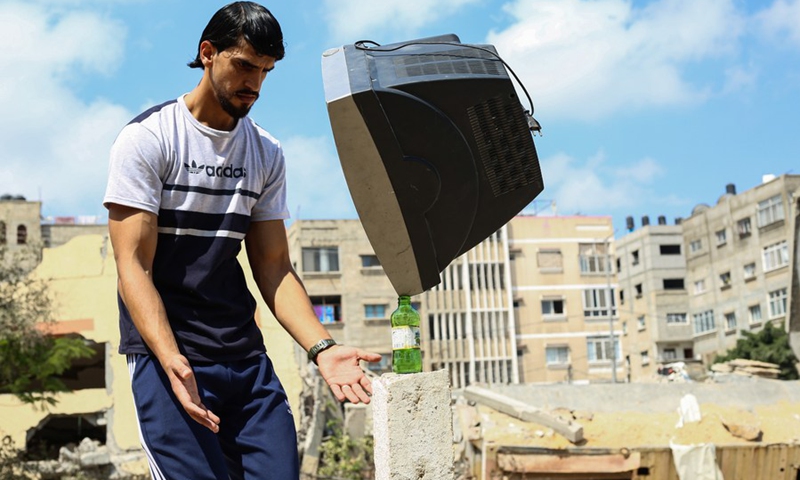 Palestinian balance artist Mohammed al-Shinbari practices balance art amid the rubble caused by recent Israeli airstrikes, in the northern Gaza Strip town of Beit Hanoun, July 10, 2021.(Photo: Xinhua)