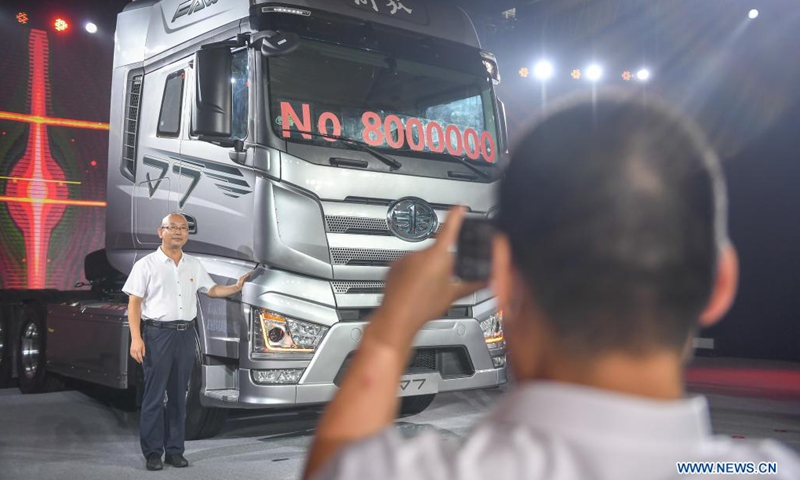 A guest poses for photos with the 8 millionth vehicle of FAW Jiefang in Changchun, northeast China's Jilin Province, July 13, 2021. FAW Jiefang, a truck subsidiary of China's leading automaker FAW Group, saw its 8 millionth vehicle roll off the production line on Tuesday.(Photo: Xinhua)