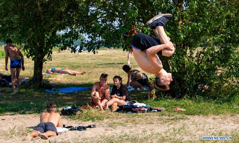 People relax in the tree shade in Riga, Latvia, on July 13, 2021. The Latvian Environment, Geology and Meteorology Center has issued a red heat warning in the country, which is in effect until Friday.(Photo: Xinhua)