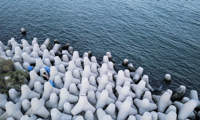 Aerial photo taken on July 4, 2021, shows a volunteer collecting garbage in between concrete tetrapods at the coast near Piraeus, Greece.(Photo: Xinhua)