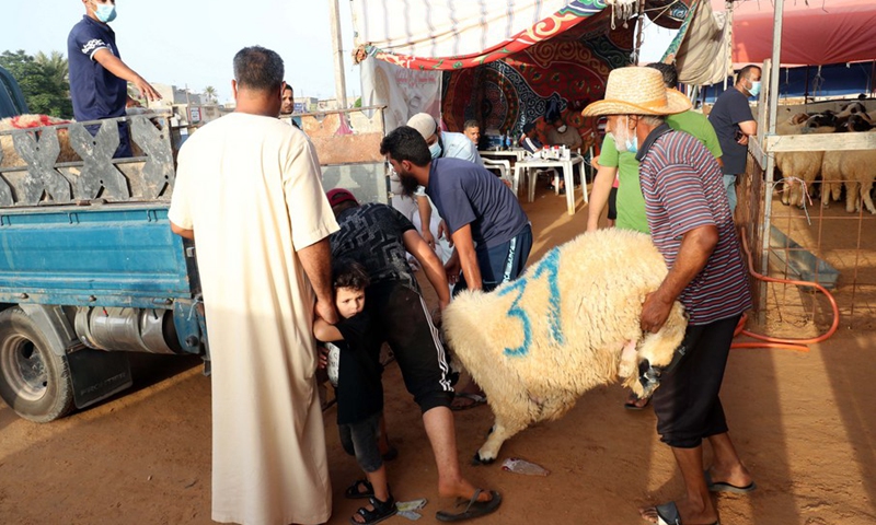 People load a sheep on a truck ahead of the Eid al-Adha festival at a market in Tajura, eastern Tripoli, Libya, July 16, 2021. (Photo: Xinhua)