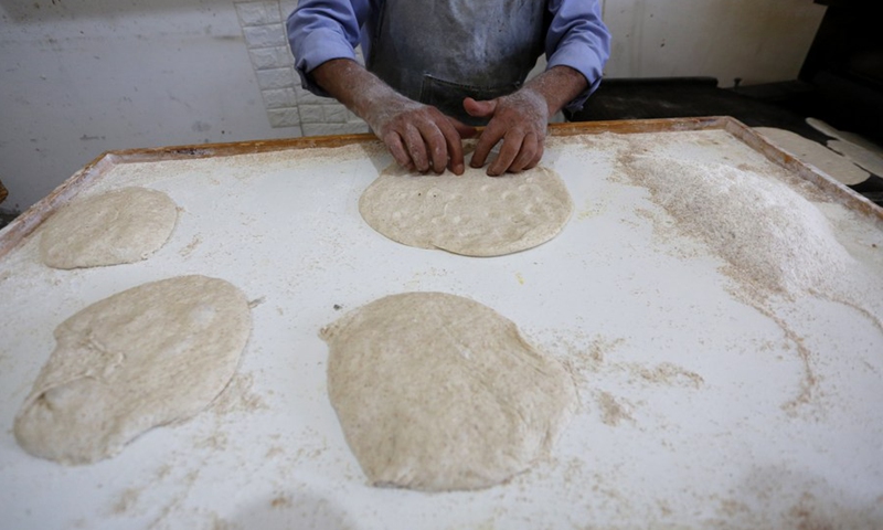 Palestinian baker Yousef Shaheen makes traditional Palestinian taboon bread at his bakery in the West Bank city of Salfit, July 13, 2021.(Photo: Xinhua)