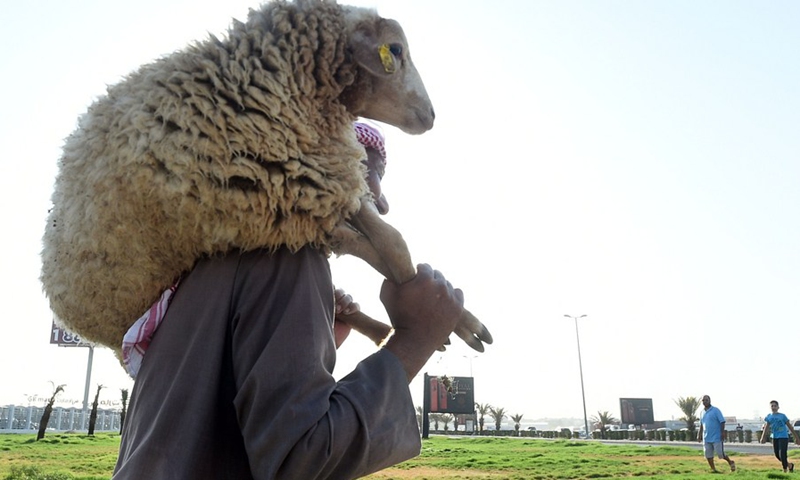 A man carries a sheep during Eid al-Adha holiday in Capital Governorate, Kuwait, July 20, 2021.(Photo: Xinhua)