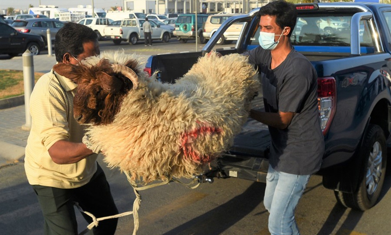 People carry a sheep during Eid al-Adha holiday in Capital Governorate, Kuwait, July 20, 2021.(Photo: Xinhua)