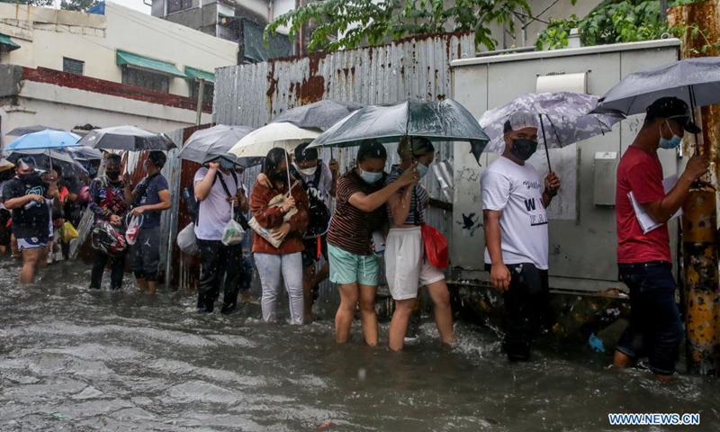People wade through the flood brought by heavy monsoon rains in Manila, the Philippines, July 21, 2021.(Photo: Xinhua)