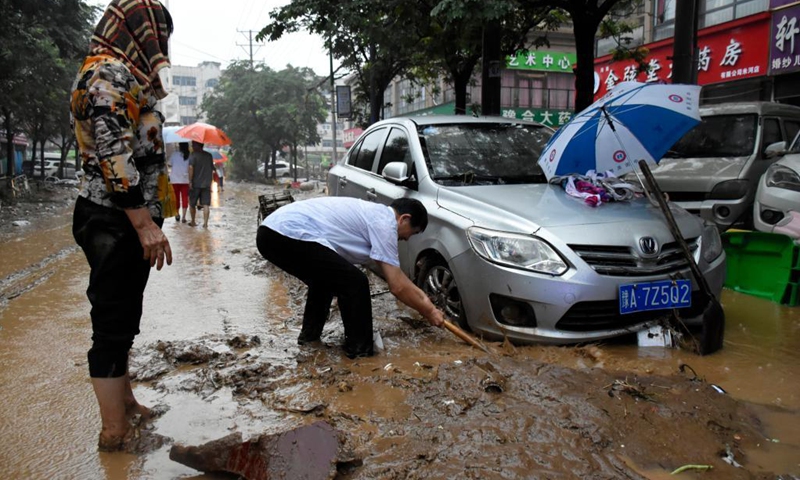 People clean up the silt around a trapped car in Mihe Town of Gongyi City, central China's Henan Province, July 21, 2021. Mihe Town suffered great damage due to the heavy rainfall on July 20, with a large number of roads damaged and vehicles flooded.(Photo: Xinhua)