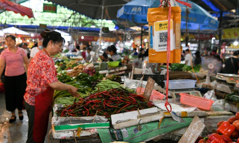 A QR code placard for mobile payment hangs over a stall at a wet market in Chengdu, southwest China's Sichuan Province, July 20, 2021.Photo:Xinhua
