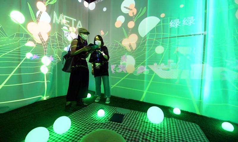 A staff member (R) guides a visitor to experience a digital art installation during the 2021 Asia Digital Art Exhibition at the Times Art Museum in Beijing, capital of China, July 23, 2021.  Photo:Xinhua