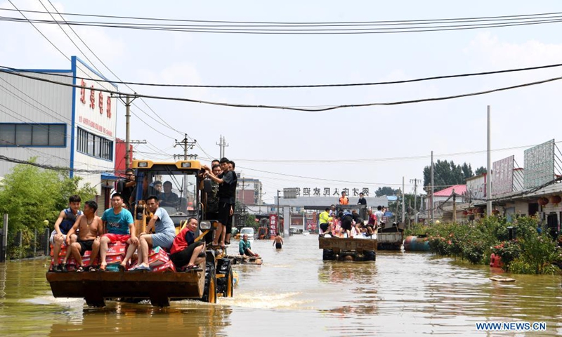 Stranded residents are evacuated on shovel loaders in flood-hit Xinxiang City, central China's Henan Province, July 24, 2021. (Photo: Xinhua)