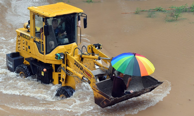 Staff members drive a shovel loader to help a local resident to evacuate from Huangzhuang Village in Weihui of Xinxiang, central China's Henan Province, July 22, 2021.(Photo: Xinhua)