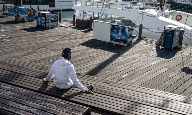 A person wearing a face mask sits on the step at the tourist attraction V&A Waterfront in Cape Town, South Africa, on June 30, 2021.(Photo: Xinhua)