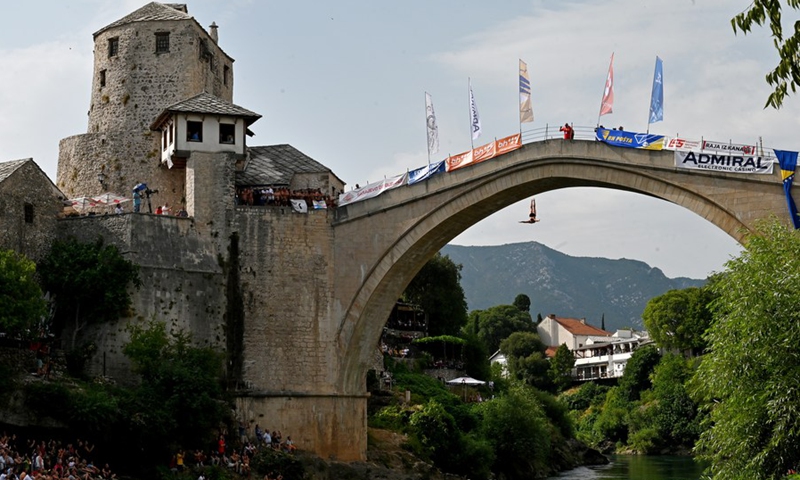 People watch a man diving off the Old Bridge during a traditional high diving competition in Mostar, Bosnia and Herzegovina, on July 25, 2021.(Photo: Xinhua)