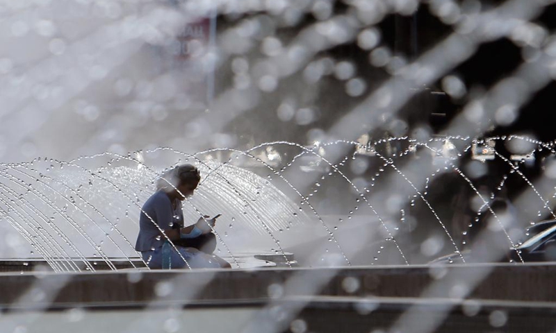 A woman sits near a fountain during a hot day in downtown Bucharest, Romania, on July 28, 2021. Romanian authorities issued an orange code, announcing a heatwave with temperatures reaching 40 degrees in the south of the Balkan country in the next few days.(Photo: Xinhua)