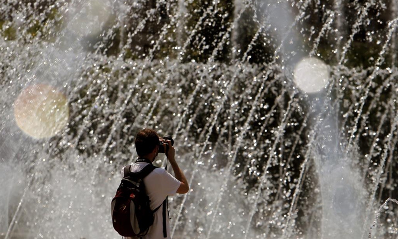 A man takes pictures of a fountain during a hot day in downtown Bucharest, Romania, on July 28, 2021. Romanian authorities issued an orange code, announcing a heatwave with temperatures reaching 40 degrees in the south of the Balkan country in the next few days.(Photo: Xinhua)