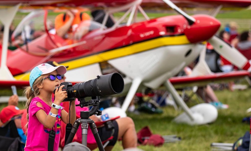 A girl takes photos at the Experimental Aircraft Association (EAA) AirVenture 2021 in Oshkosh, Wisconsin, the United States, July 30, 2021. The EAA AirVenture, an annual air show that gathering aviation enthusiasts, is ongoing from July 26 to Aug. 1, 2021.Photo:Xinhua