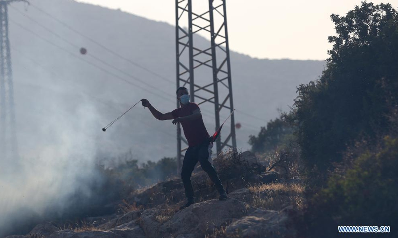 A Palestinian protester uses a slingshot to hurl a stone at Israeli soldiers during clashes following a protest against the expanding of Jewish settlements at Tayasir checkpoint, east of the West Bank city of Tubas, July 31, 2021.(Photo: Xinhua)