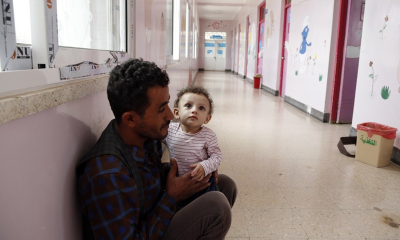 A father holds his malnourished child in the corridor of the anti-malnutrition treating ward, waiting for urgently-needed medical treatment at a hospital in Sanaa, Yemen, on July 31, 2021.(Photo: Xinhua)