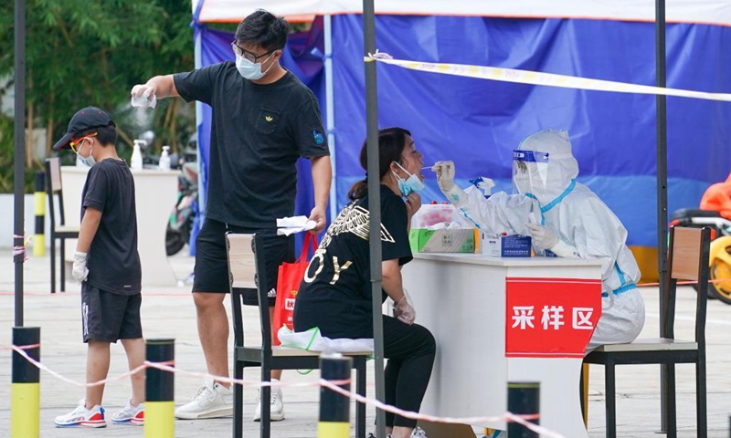 A medical worker takes a throat swab sample from a woman at a nucleic acid testing site in Yangzhou, east China's Jiangsu Province, Aug. 14, 2021. The city of Yangzhou launched a new round of mass nucleic acid testing in key areas on Saturday.Photo:Xinhua