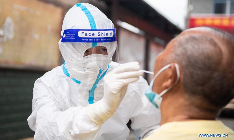 Luo Jinwu takes a throat swab sample from a resident for nucleic acid testing in Yangping Village of Yongding District in Zhangjiajie City, central China's Hunan Province, Aug. 12, 2021.Photo:Xinhua