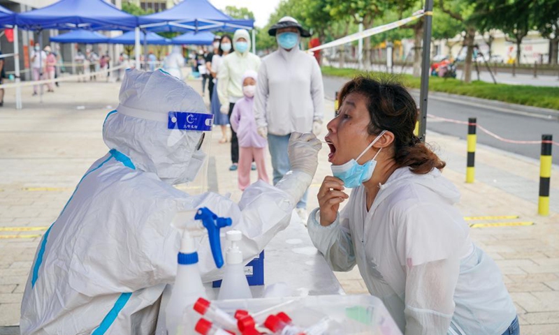 A medical worker takes a throat swab sample from a woman at a nucleic acid testing site in Yangzhou, east China's Jiangsu Province, Aug. 14, 2021. The city of Yangzhou launched a new round of mass nucleic acid testing in key areas on Saturday. Photo:Xinhua