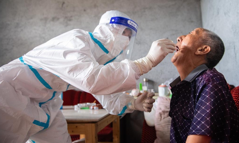 Luo Jinwu takes a throat swab sample from a resident for nucleic acid testing in Yangping Village of Yongding District in Zhangjiajie City, central China's Hunan Province, Aug. 12, 2021.Photo:Xinhua