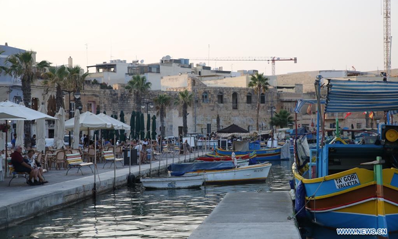 People spend time at dusk at a harbor in Marsaxlokk, a fishing village in Malta, on Aug. 14, 2021.(Photo: Xinhua)