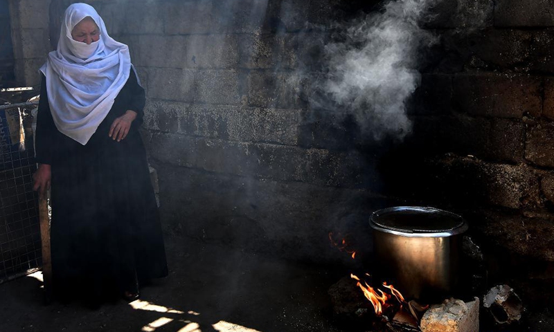 Nabiha Badour, a 75-year-old Syrian woman, lights up firewood in the backyard of her village house in the countryside of Sweida province, southern Syria, on June 21, 2021. Nabiha Badour refuses to stay home and wait for sons to take care of her. Instead, she chooses to do hard work to make her own living amid the harsh economic situation in the country.(Photo: Xinhua)