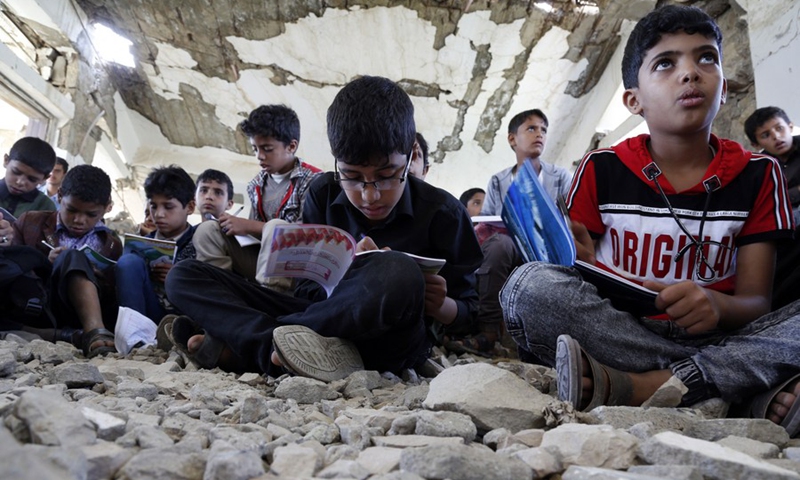 School children sit on the ground inside a half-collapsed teaching building at Alwahdah school in Al-Radhmah district in Ibb province, about 190 km south of the Houthi-held capital Sanaa, Yemen, on Aug. 14, 2021.(Photo: Xinhua)