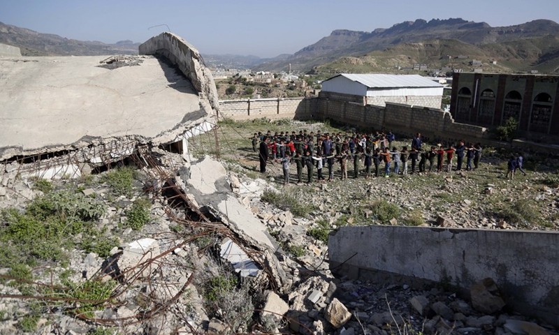 Students do morning exercise in front of a half-collapsed building at Shuhada-Alwahdah School in Al-Radhmah district of Ibb province, Yemen, Aug. 14, 2021.(Photo: Xinhua)