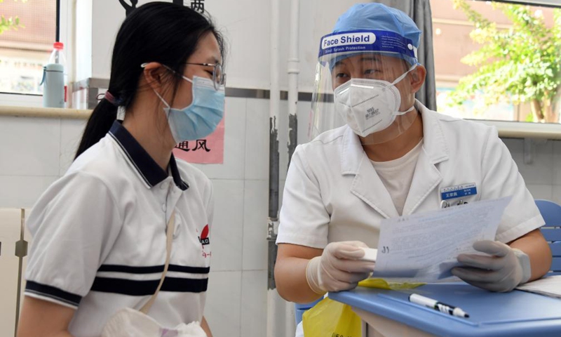 A medical worker inquires a girl student of her health condition before she receives a dose of COVID-19 vaccine at the Hangtian Campus of the Beijing Yuying School in Beijing, capital of China, on Aug. 21, 2021.Photo:Xinhua