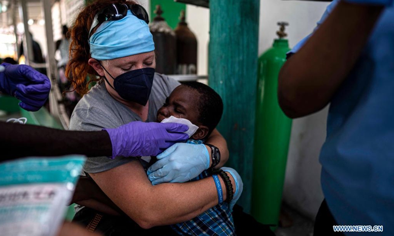 A paramedic hugs a child as he is treated at a hospital in Les Cayes, Haiti, on Aug. 22, 2021. The number of people killed by the 7.2-magnitude earthquake on Aug. 14 in Haiti has risen to 2,207, with 344 still missing, the country's civil protection agency reported on Sunday.(Photo: Xinhua)