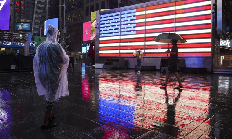 People are seen in the rain caused by tropical storm Henri, in Times Square in New York, the United States, on Aug. 22, 2021. (Photo: Xinhua)