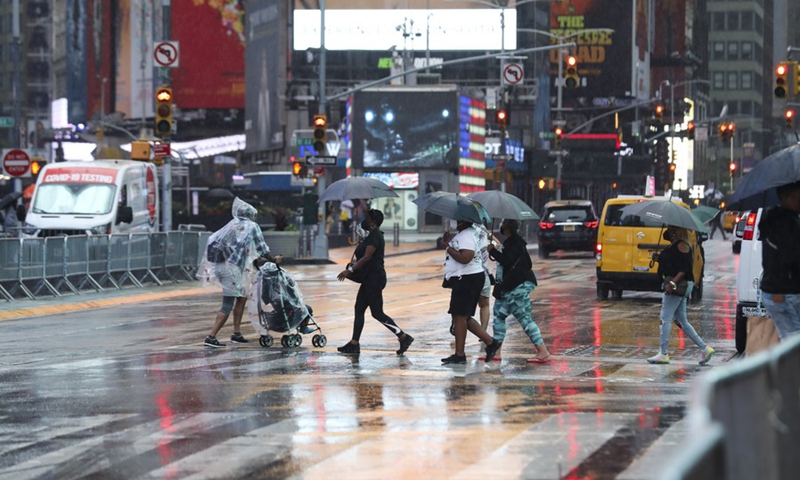 Pedestrians cross a street in the rain caused by tropical storm Henri, in Times Square in New York, the United States, on Aug. 22, 2021.(Photo: Xinhua)